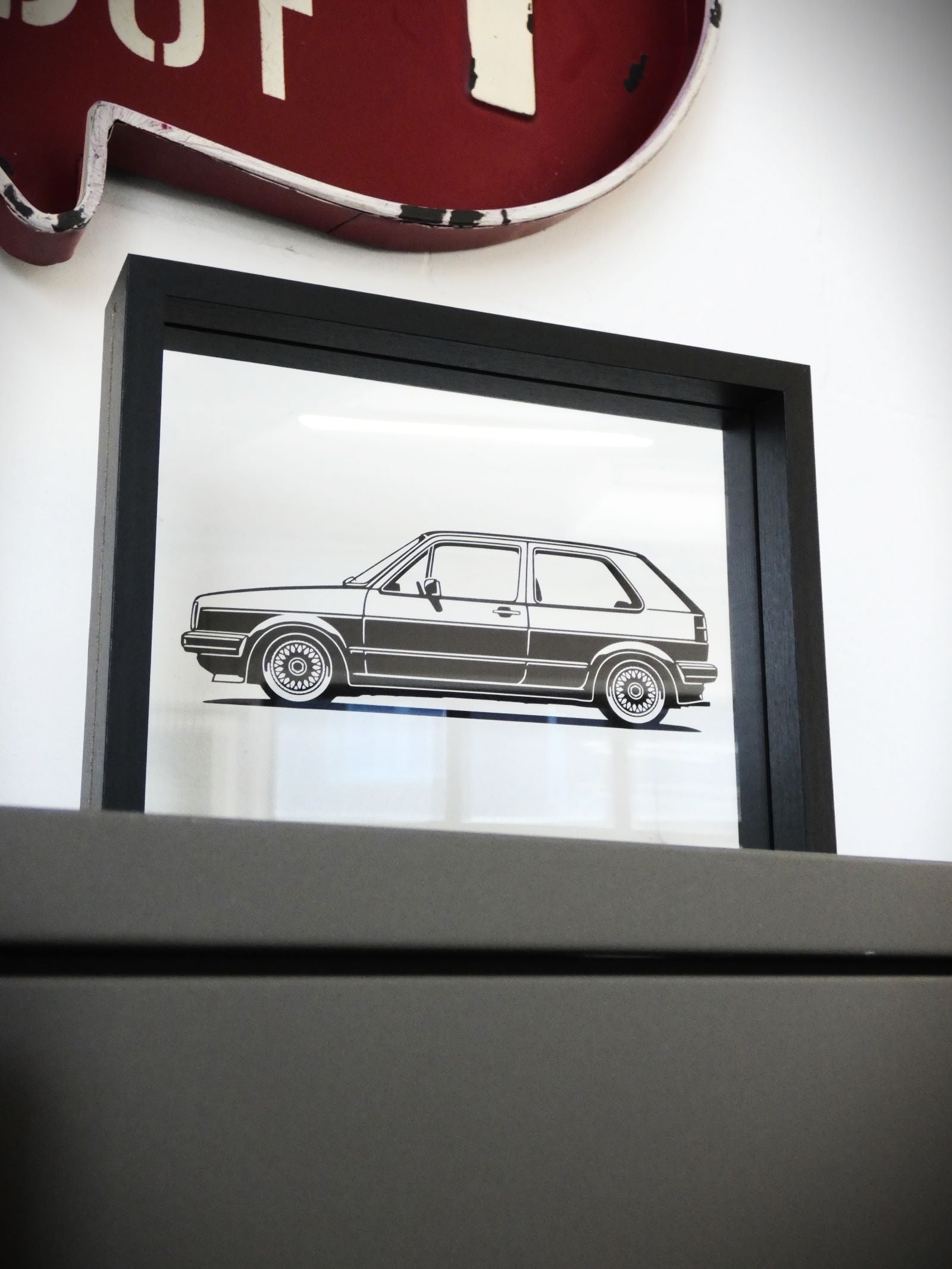 Auto Silhouette eines Volkswagen Golf Zwei als Aufkleber Sticker verklebt im Rahmen hinter Glas als Deko